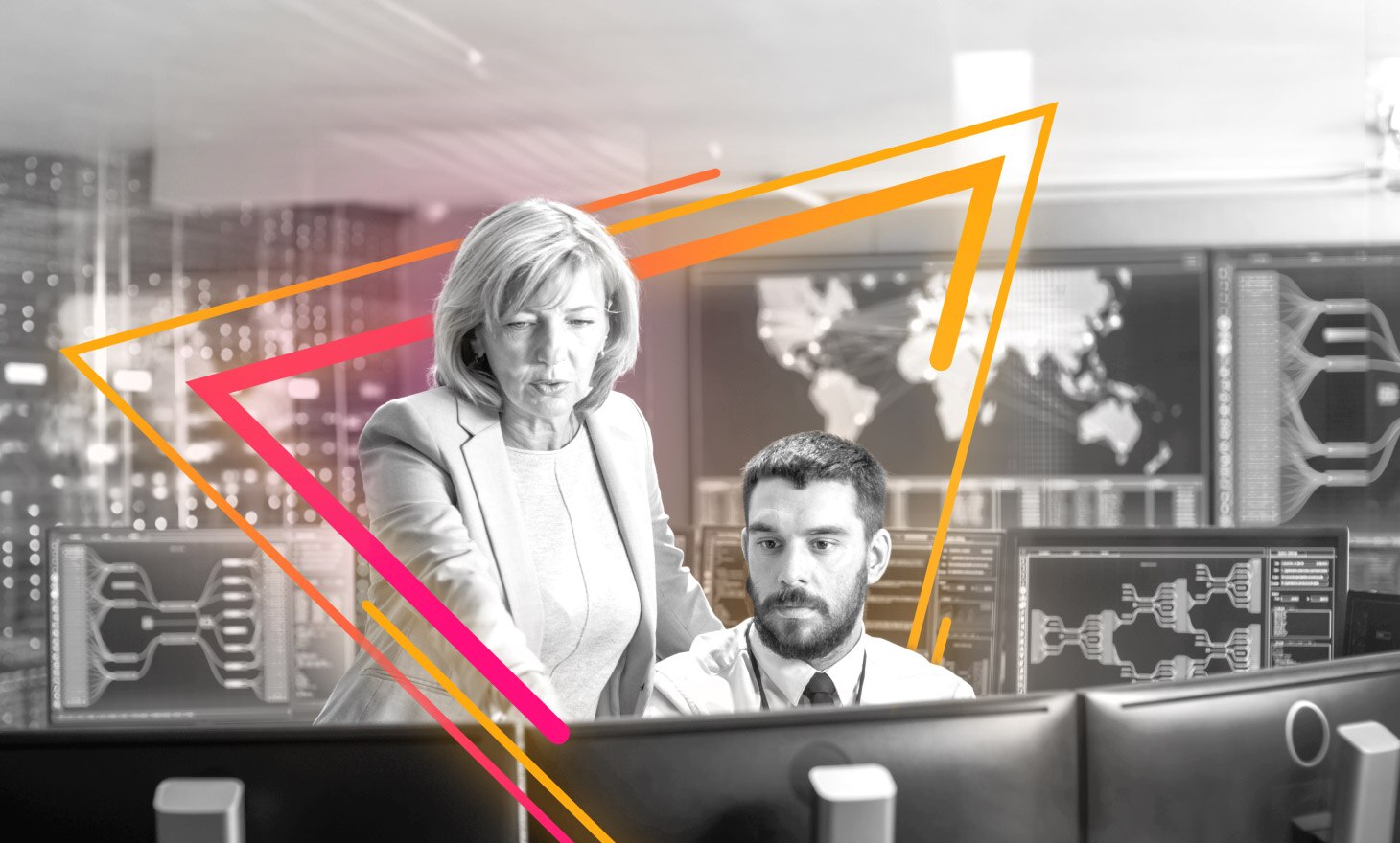 A standing woman in business attire points at the computer monitor of a seated employee. They are framed with rays of light.